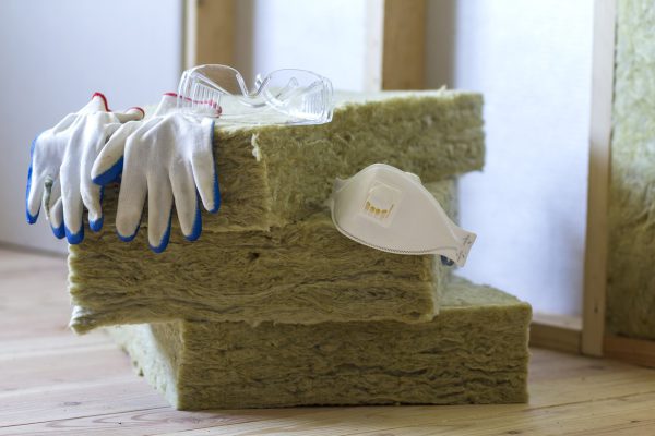 Rock wool and fiberglass insulation staff material for cold barrier. Tools for work with glass wool: protective goggles, glasses and mask. Warm home, economy, construction and renovation concept.
